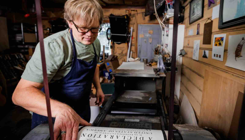 Utah artist Rob Buchert examines a freshly printed sheet of his recreation of the 1776 Declaration of Independence from the press. Every copy was printed one sheet at a time, by hand, on paper he made himself using 18th century methods